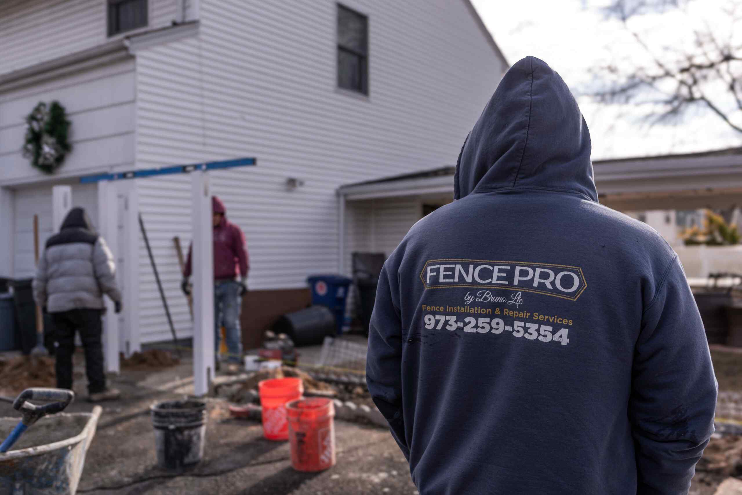 Fence Pro by Bruno installer in branded hoodie overseeing a crew at a residential install
