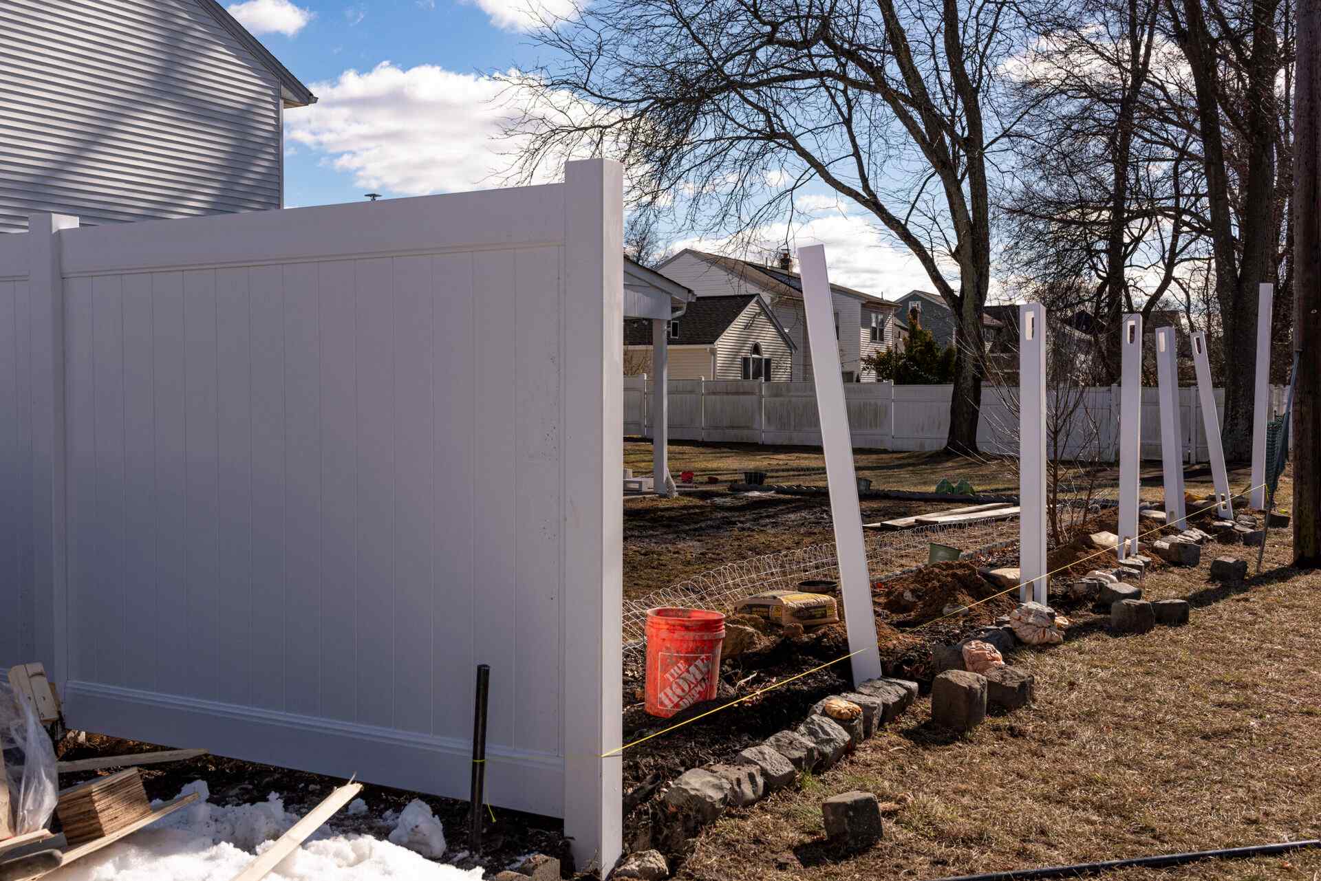 White vinyl fence install in progress — posts set, panels going up in a Wayne NJ backyard